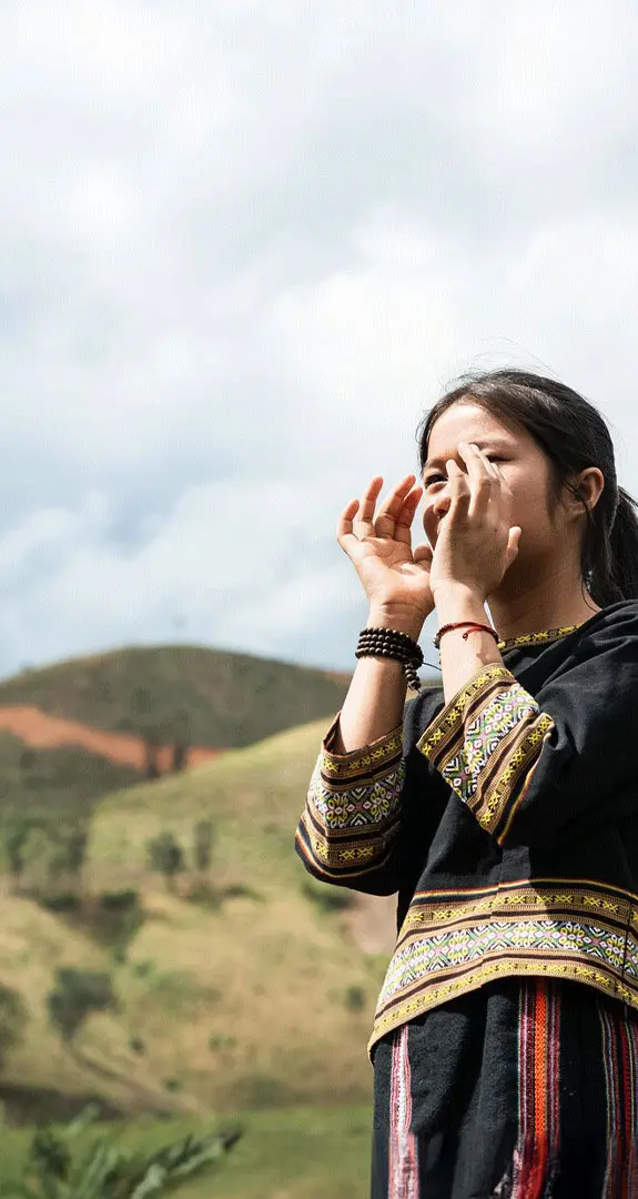 Y Kieu calling through her hands with green hills in background