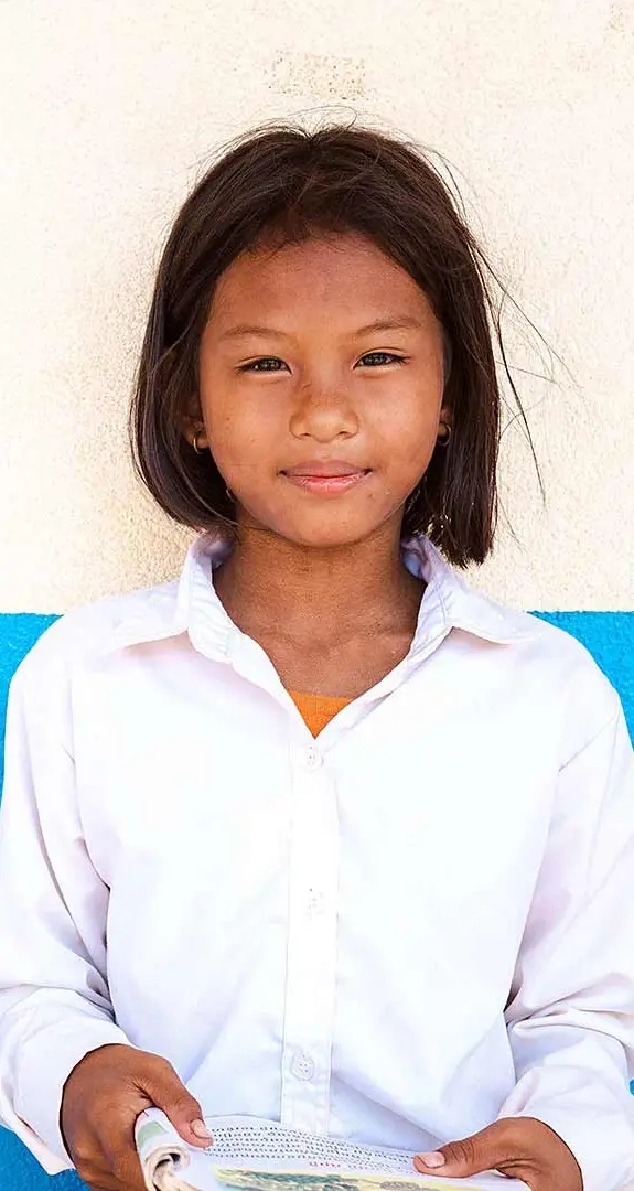 Muta, 11, standing in front of a white and blue wall.