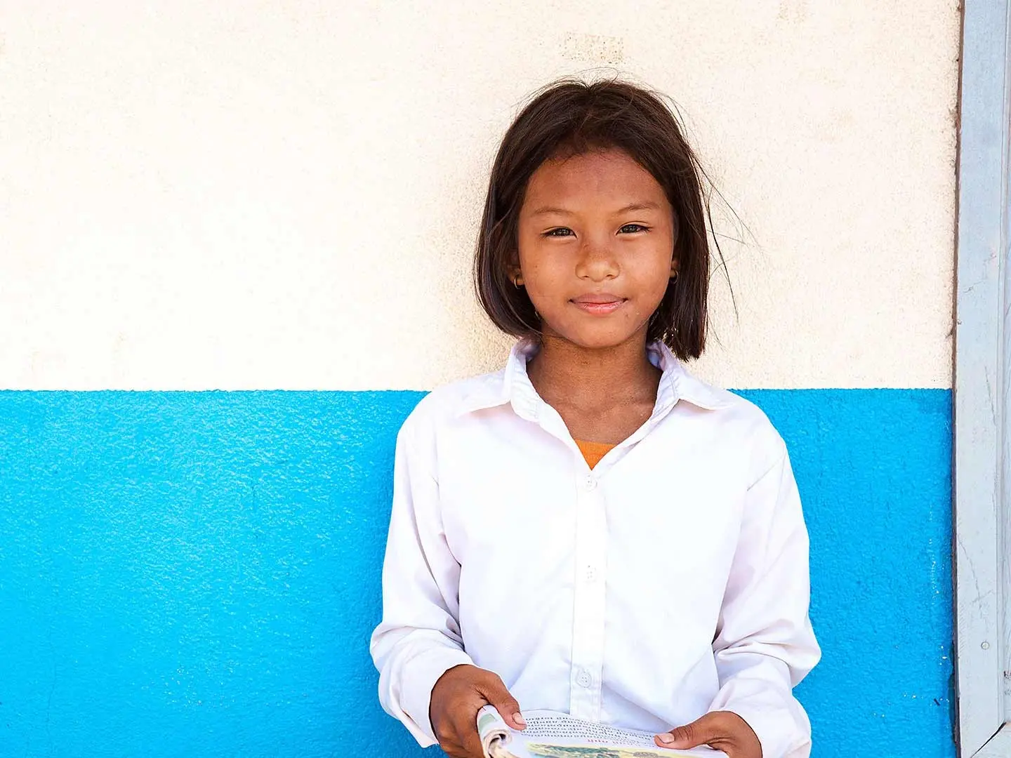 Muta, 11, standing in front of a white and blue wall.