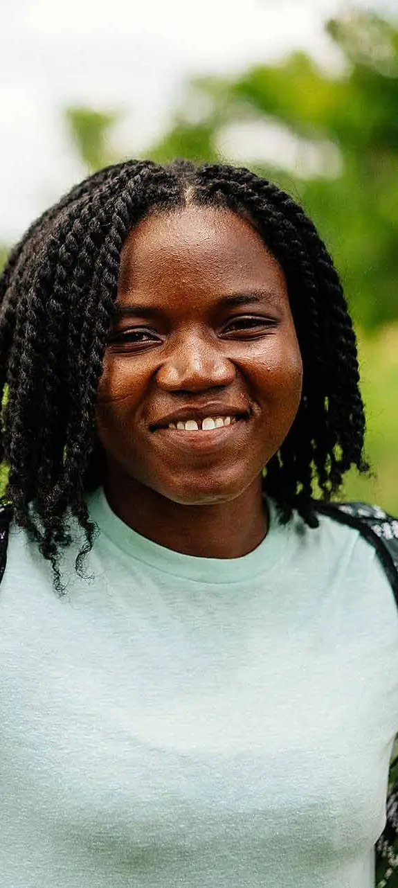 Doris, 27, a maize and soybean farmer, standing in a field on her farmland