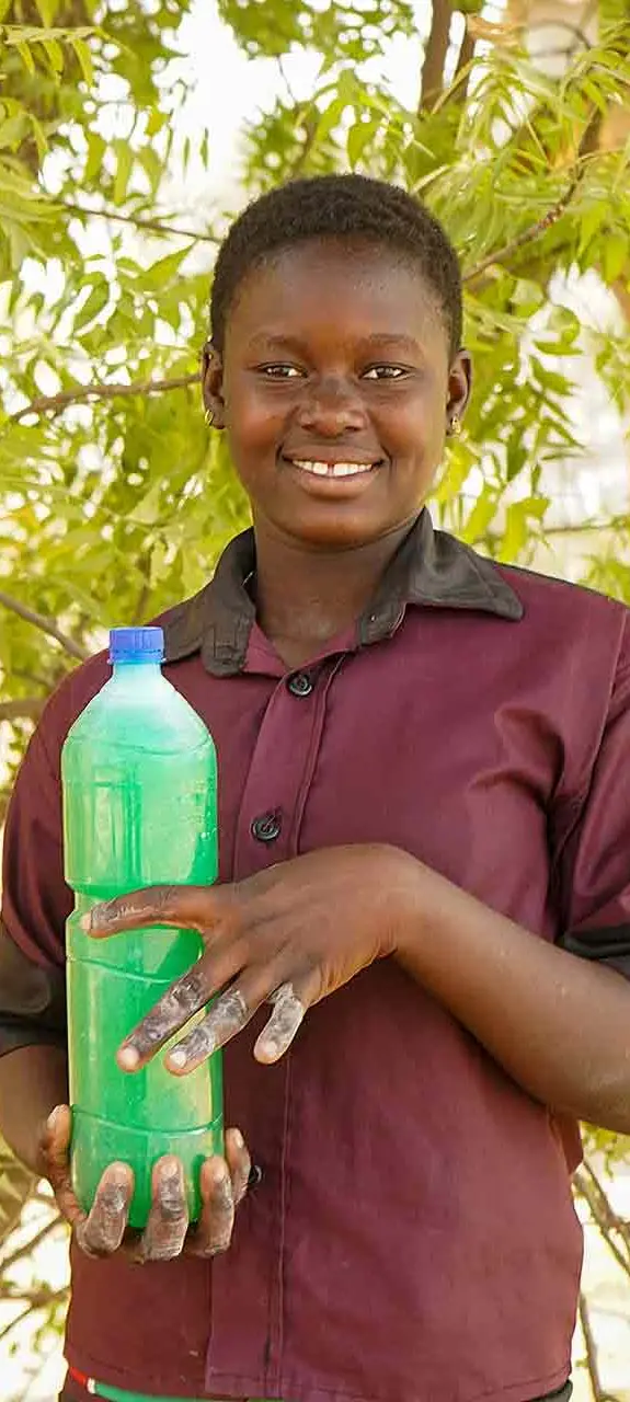 Jemima, 18, holding a bottle of the liquid soap she makes in Burkina Faso.