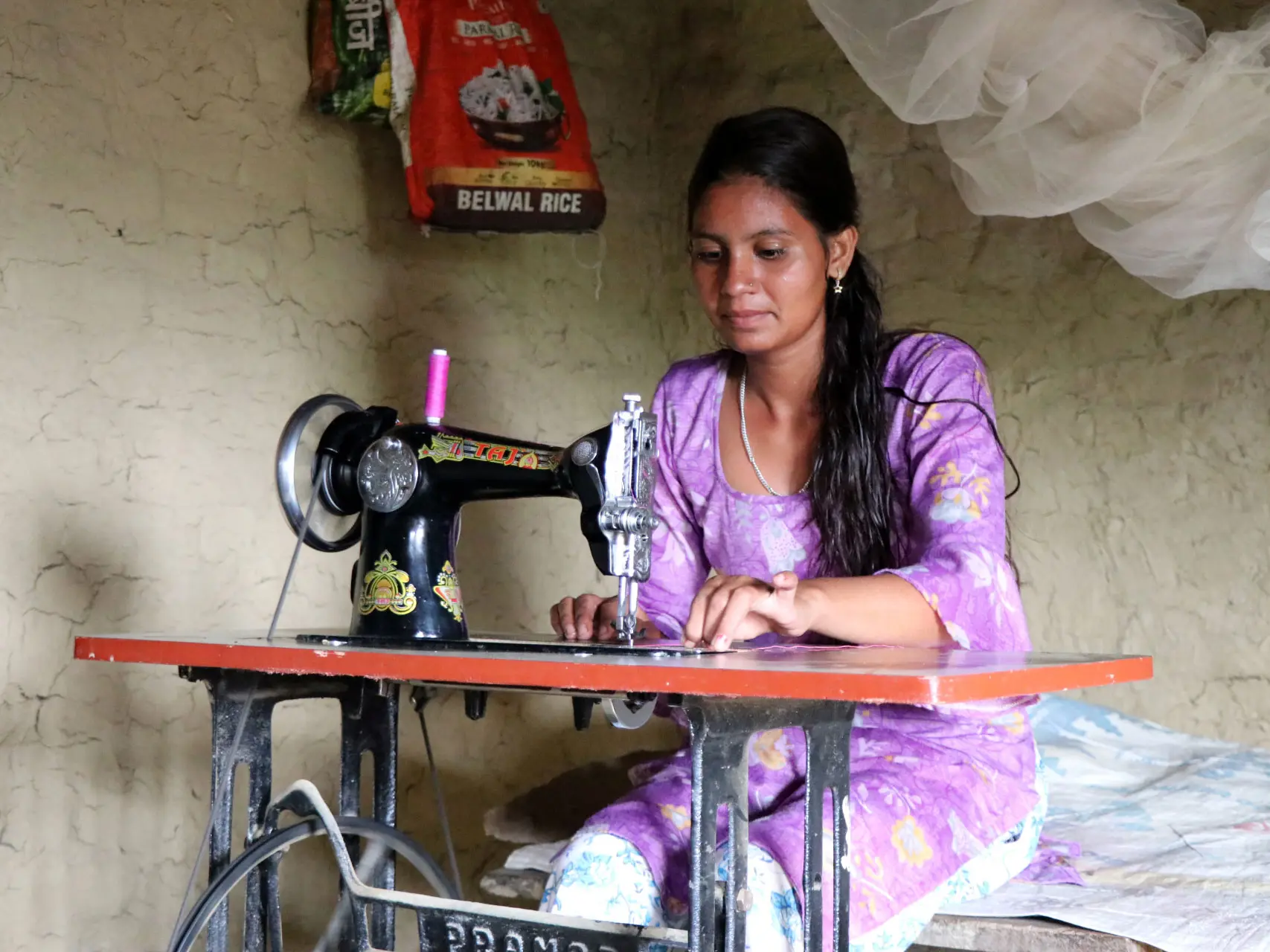 Parbati uses her sewing machine to make clothes at her home