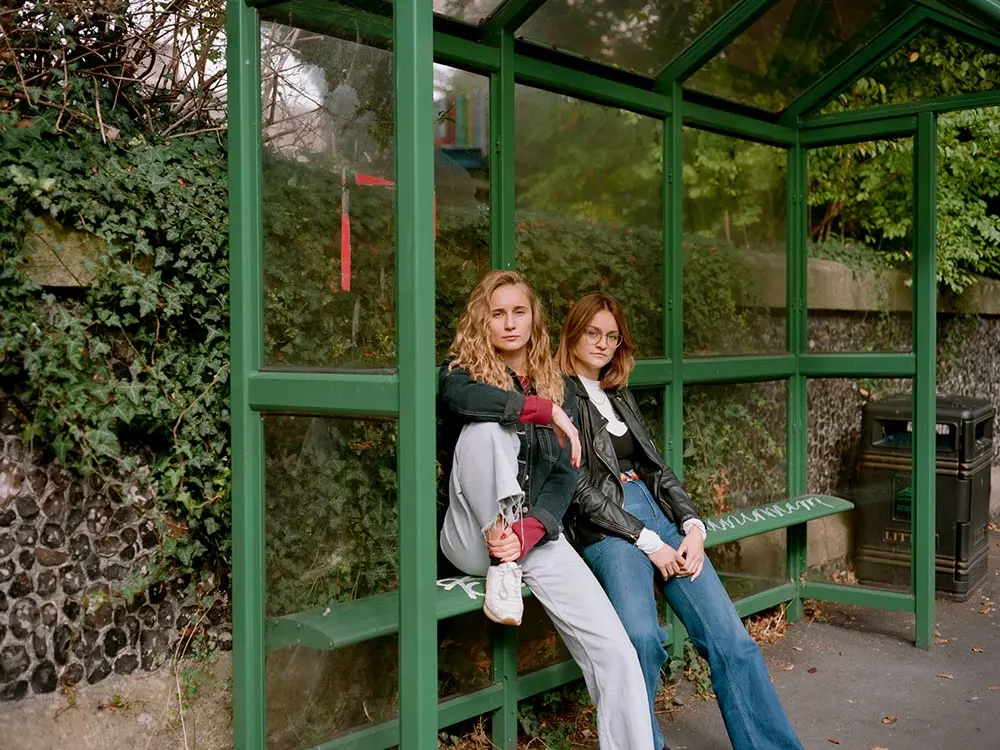 Maya and Gemma sitting on a bench in their home town